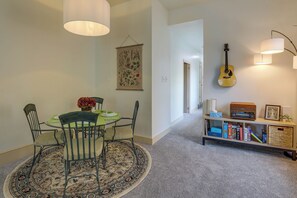 A dining area with a round table, chairs, and a patterned rug. There is a bookshelf with books and a guitar on the wall. - Walk to Downtown! Central 2-Apt Combo in Pottstown (Pottstown)