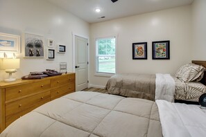 A bedroom with two beds, a dresser, a lamp, and artwork on the walls. - 'The Romano Retreat' Modern Lake Guntersville Home (Scottsboro)