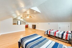 A spacious attic bedroom with two beds, a ceiling fan, and a skylight.