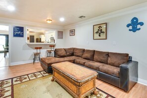 A living room with a brown sectional sofa, a wooden coffee table, and a kitchen in the background. - Louisiana Group Retreat! Dual Units Near Hunting (Iowa)