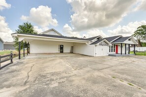Ein eingeschossiges Gebäude mit überdachter Garage und einem kleinen Anbau mit roter Tür.