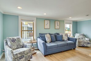A living room with a blue sofa, patterned armchairs, and framed artwork on the wall. - Ocean & Marsh Views! Wells Condo w/ Outdoor Space (Wells)
