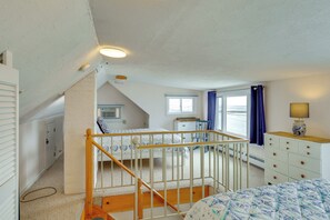 Ein Schlafzimmer mit Bett, Kommode und einem Fenster mit Blick.