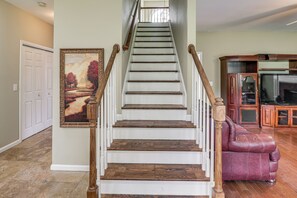 Eine Treppe mit Holzsitzgelegenheiten und weißen Geländern, ein gerahmtes Gemälde an der Wand und ein Ledersofa im Wohnzimmer.