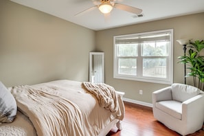 Ein Schlafzimmer mit Bett, Stuhl, Fenster und Deckenventilator.