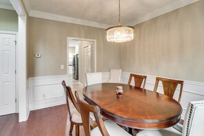 Ein Esszimmer mit einem runden Holztisch, sechs Stühlen und einer Chandelier.