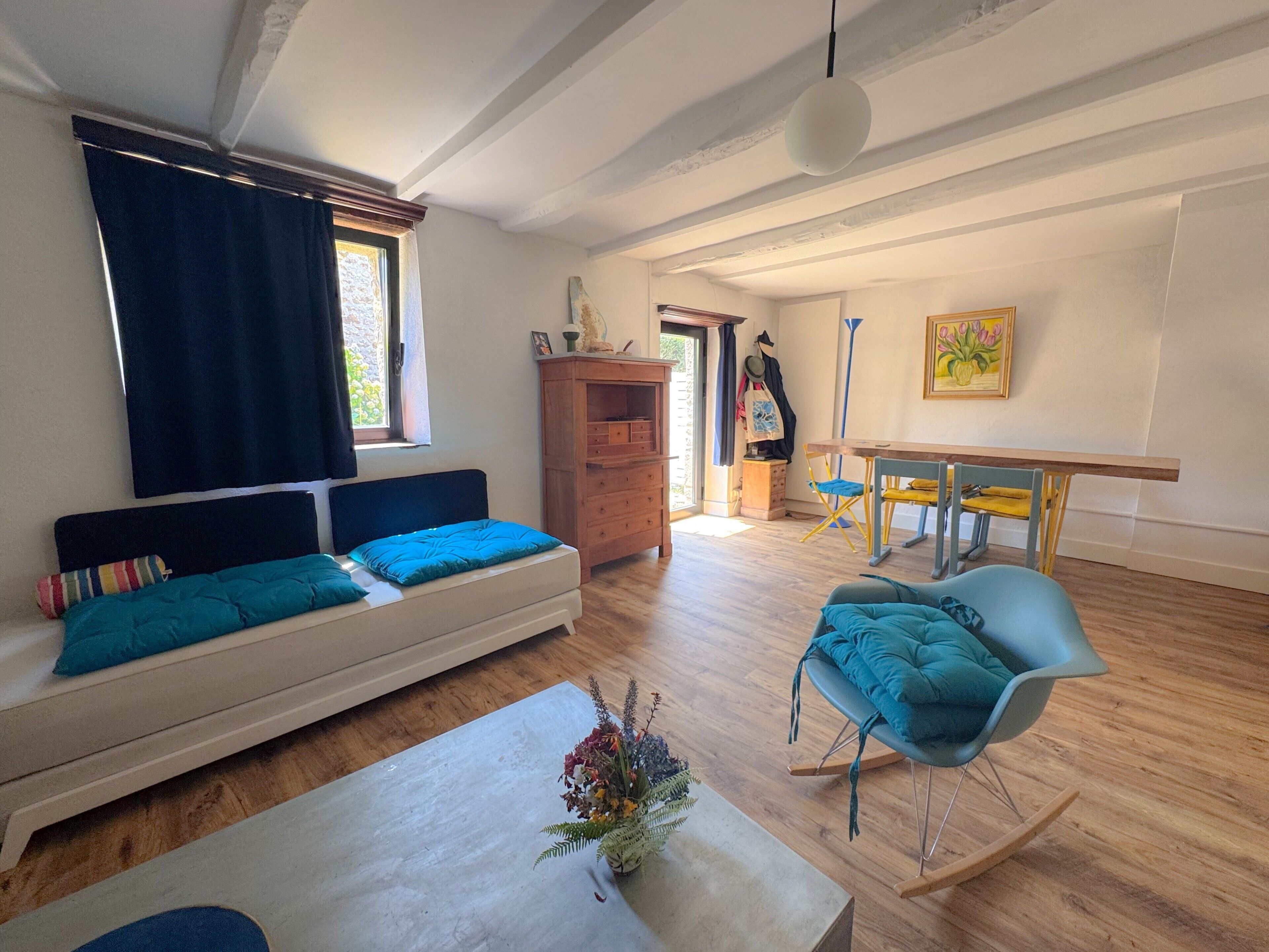 A living room with a sofa, a table, a chair, and a wooden cabinet.