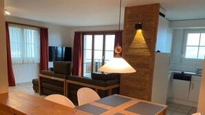 En moderne stue med et træspisebord, en sofa og et fjernsyn.