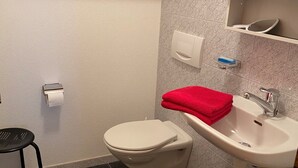 Et badeværelse med toilet, vask og en hylde med et håndklæde.