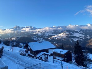 Eine verschneite Berglandschaft mit einem Haus im Vordergrund.