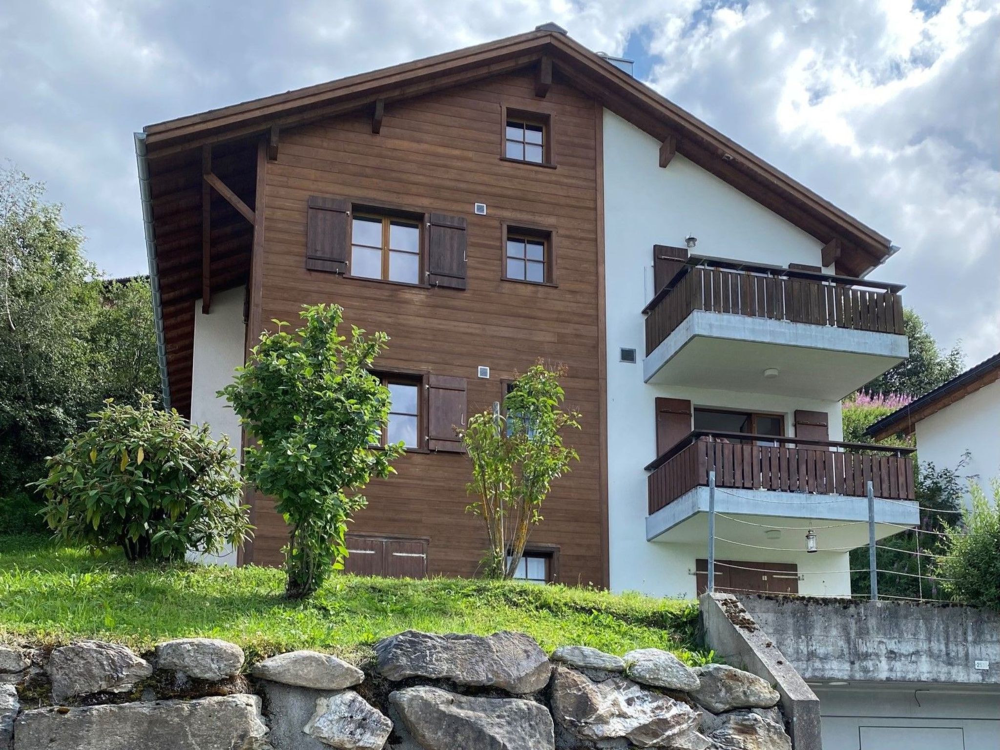 A multi-story building with a wooden facade, multiple windows, and a balcony.
