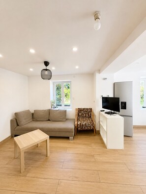 A modern living room with a sofa, a patterned armchair, a TV, and a white cabinet. - Cozy home - near Val Thorens / Orelle (Saint-Julien-Mont-Denis)