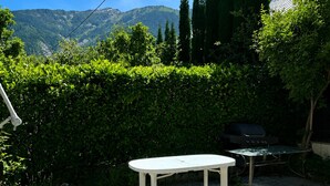Eine Terrasse im Freien mit einem weißen Tisch und einem Grill.