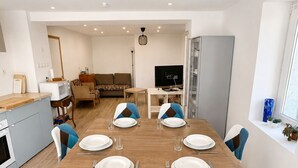 Ein stilvoller Essbereich mit einem Holztisch, vier Stühlen und einem Fernseher im Hintergrund.