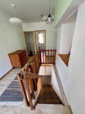 A multi-level interior with a wooden staircase, a hanging light fixture, and a view into an adjacent room. - Cozy House - Near Val Thorens / Orelle (Saint-Julien-Mont-Denis)