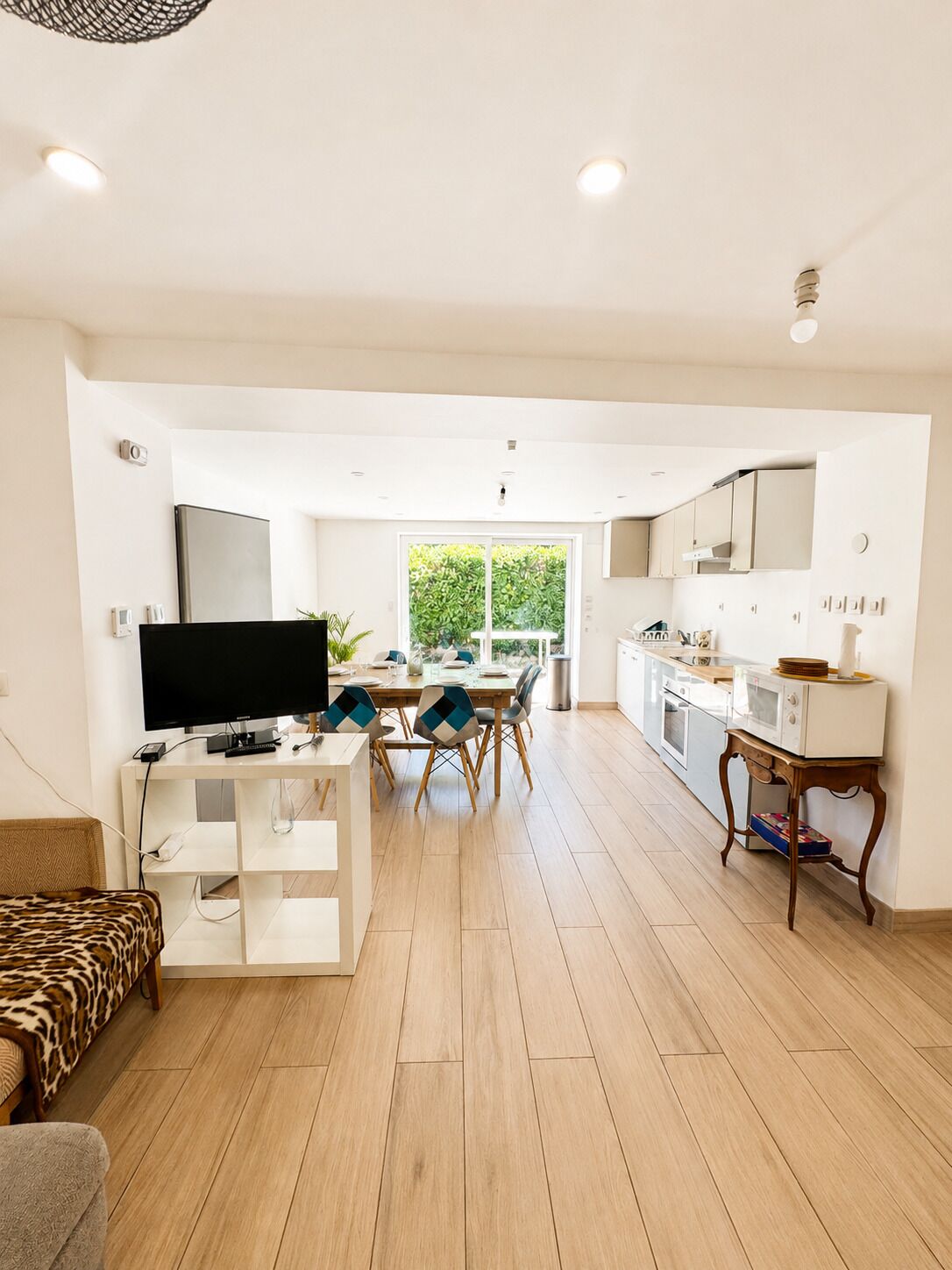 A spacious living area with a flat-screen TV, dining table, and chairs.