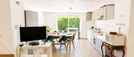 A spacious living area with a flat-screen TV, dining table, and chairs.