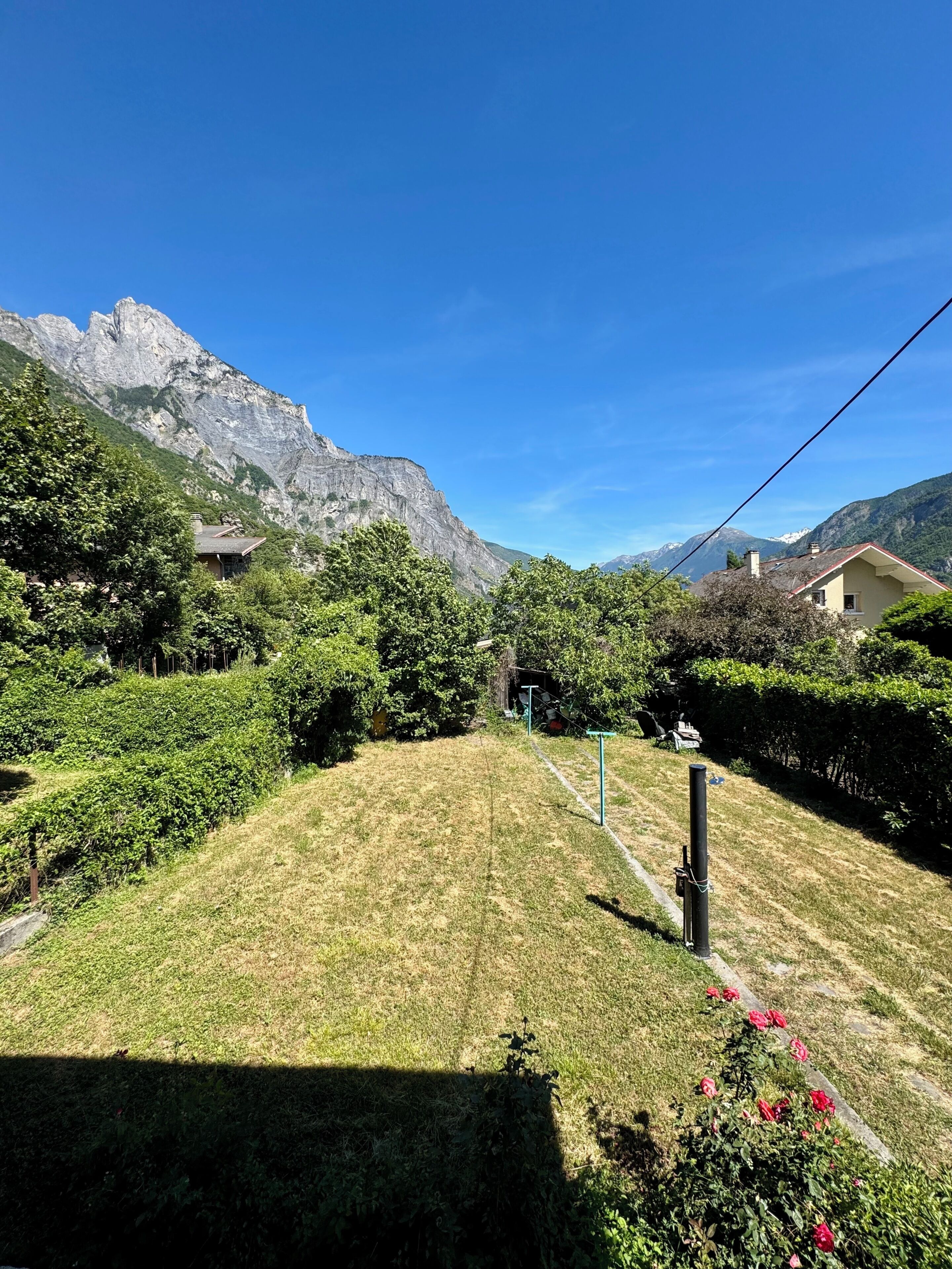 Ein Wohngebiet mit Häusern, einer grünen Rasenfläche und Bergen im Hintergrund.