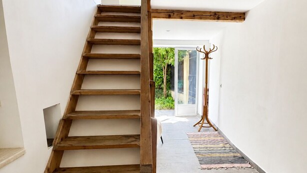 Eine Holztreppe mit Blick auf einen Garten durch eine Glastür am Obergeschoss.