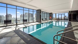 A modern indoor swimming pool with large windows and a city view.