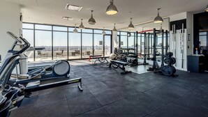 A gym with exercise equipment, large windows, and a city view.