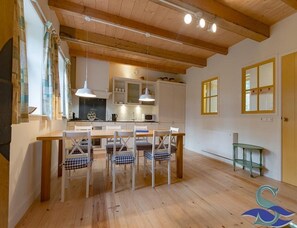 A modern kitchen with wooden beams, a dining area with checkered chairs, and a green side table. - Spacious Coastal Home in Koudekerke (Koudekerke)