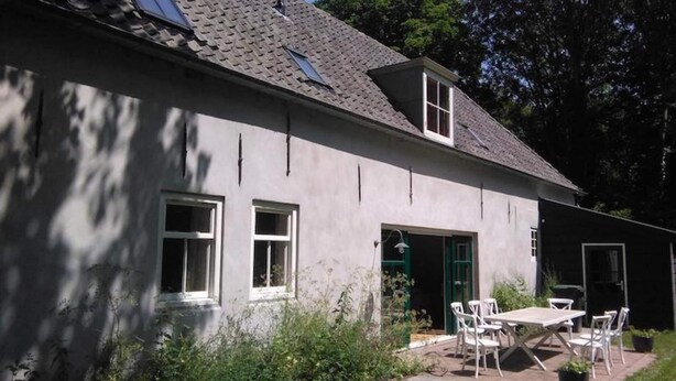 A house with a grey exterior, a tiled roof, and a small patio with a table and chairs. - Spacious Coastal Home in Koudekerke (Koudekerke)