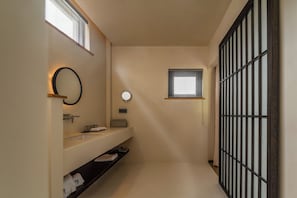 Quarto casal básico de uso individual, vista para o jardim | Banheiro | Chinelos, sabonete, shampoo, papel higiênico