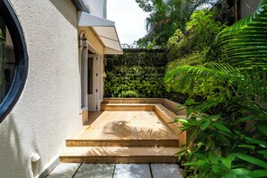 A modern building with a concrete exterior, a wooden staircase leading to a door, and lush greenery surrounding the entrance. - Staymaster Trivala-3BR Villa with Pool  (Calangute)