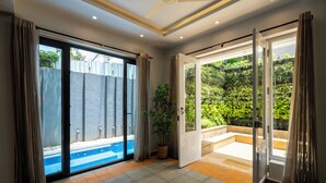 Une pièce dotée d’une porte-fenêtre coulissante donnant sur une piscine, d’une plante en pot et d’un ventilateur de plafond.