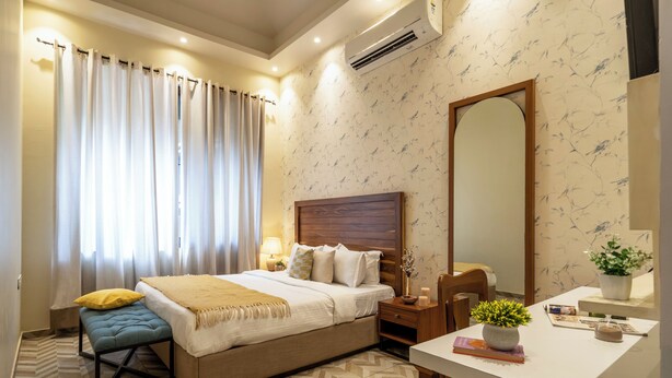 Une chambre d’hôtel comprenant un lit, une table de chevet, une chaise, un bureau et un grand miroir.