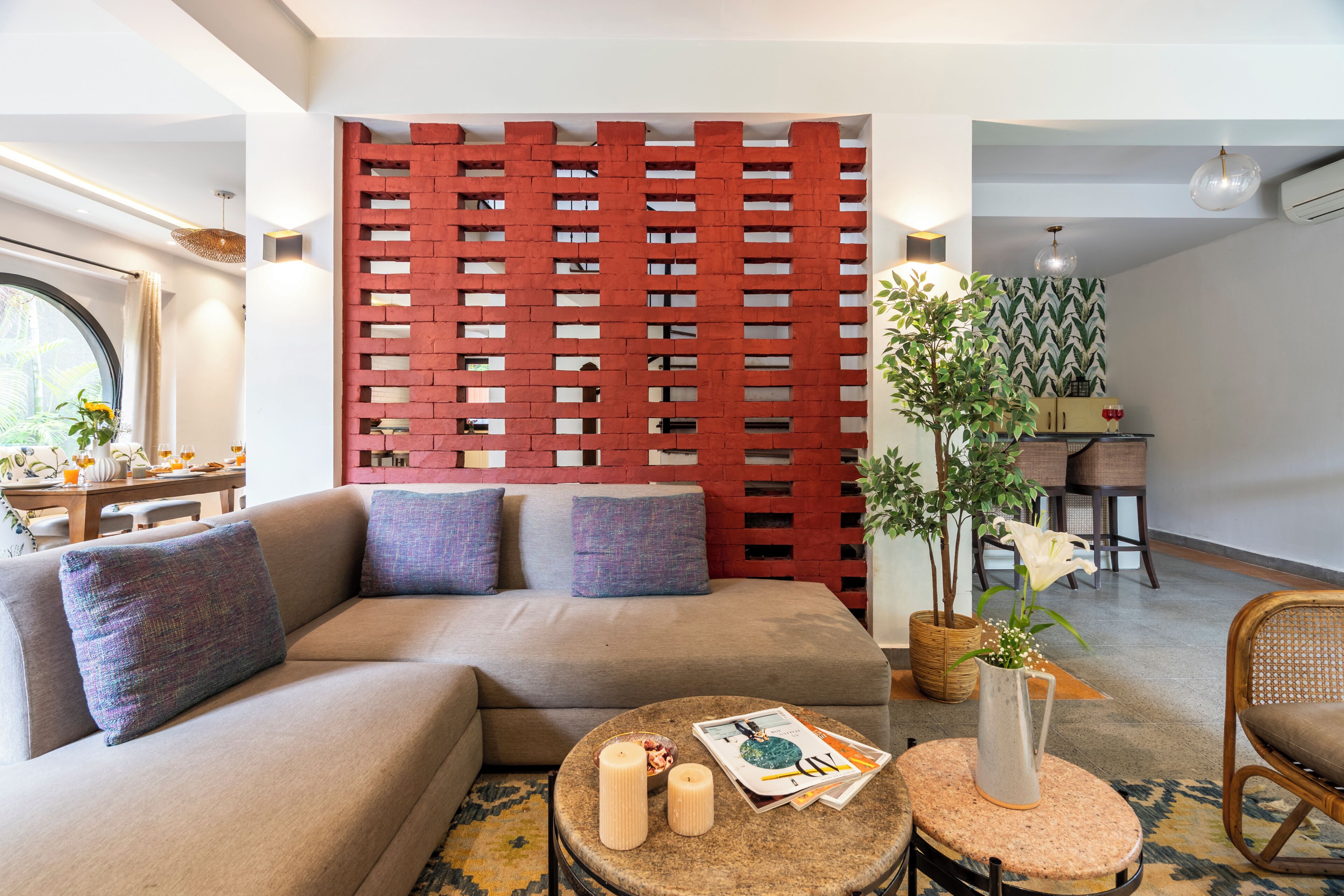 A modern living room with a sectional sofa, a round coffee table, and a decorative wall panel.