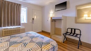 Une chambre d’hôtel comprenant un lit, une armoire, un coin salon et un téléviseur.
