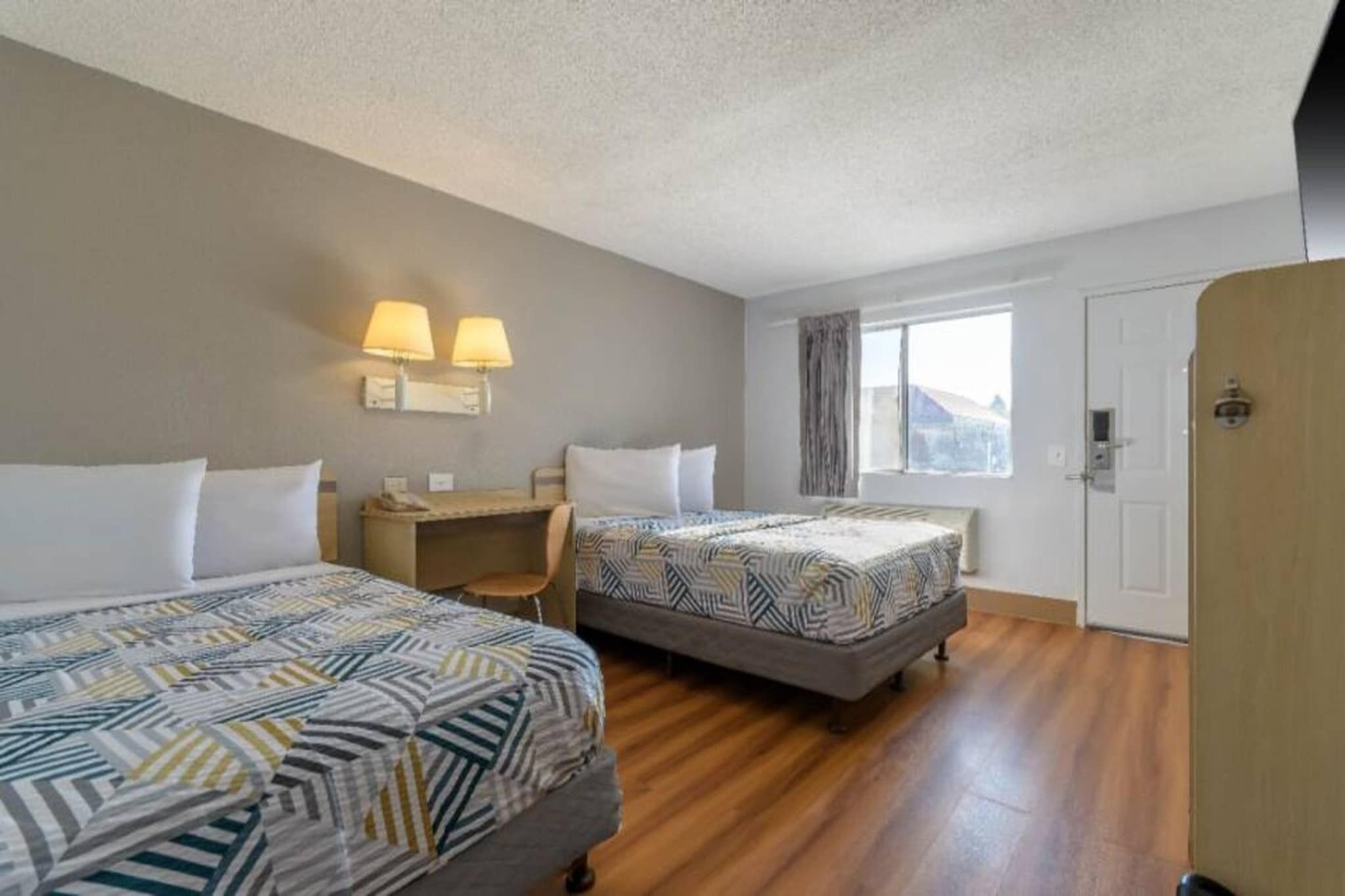 Ein Hotelzimmer mit zwei Betten, einem Schreibtisch und einem Fenster.