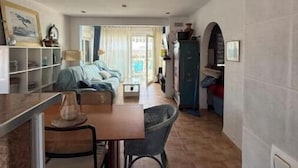 En kompakt opholdsstue med spiseplads, en sofa og et tekøkken.