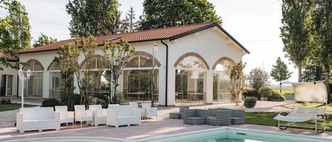 A poolside area with outdoor seating, a swimming pool, and a building with arched windows.