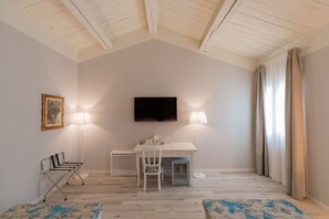 Una habitación con una mesa blanca, dos sillas, un televisor y dos lámparas.