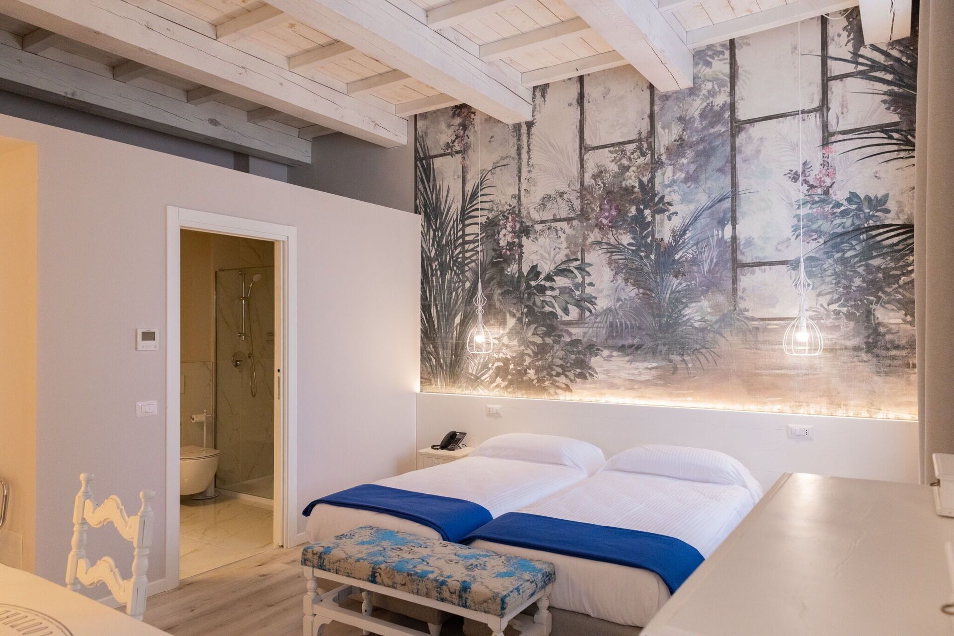 A bedroom with a bed, bedside table, and a large wall mural.