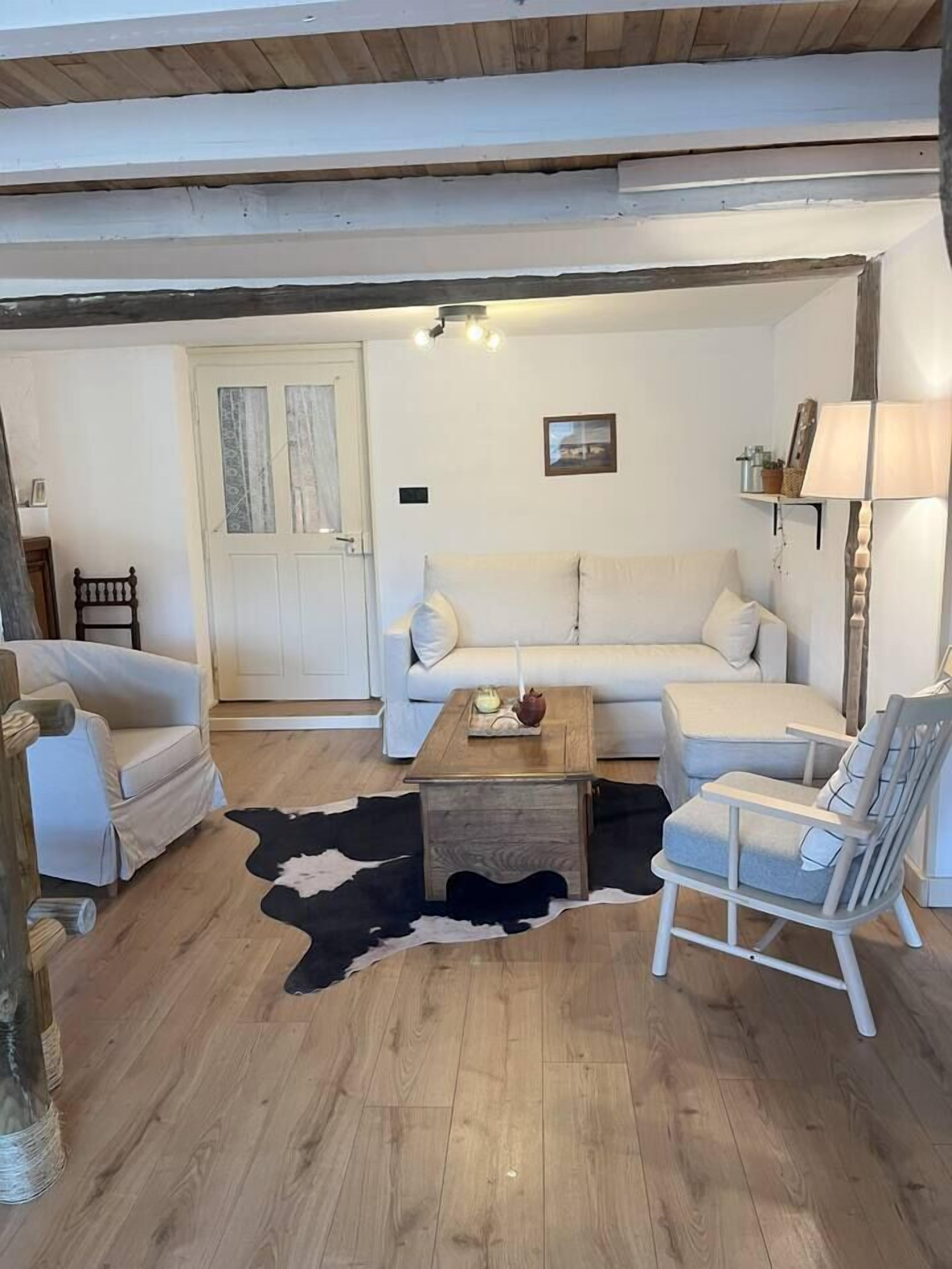 A cozy living room with a sofa, chairs, a coffee table, and a cowhide rug.
