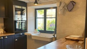 Una cocina con armarios oscuros, encimera de madera, ventana con vistas y un perchero.