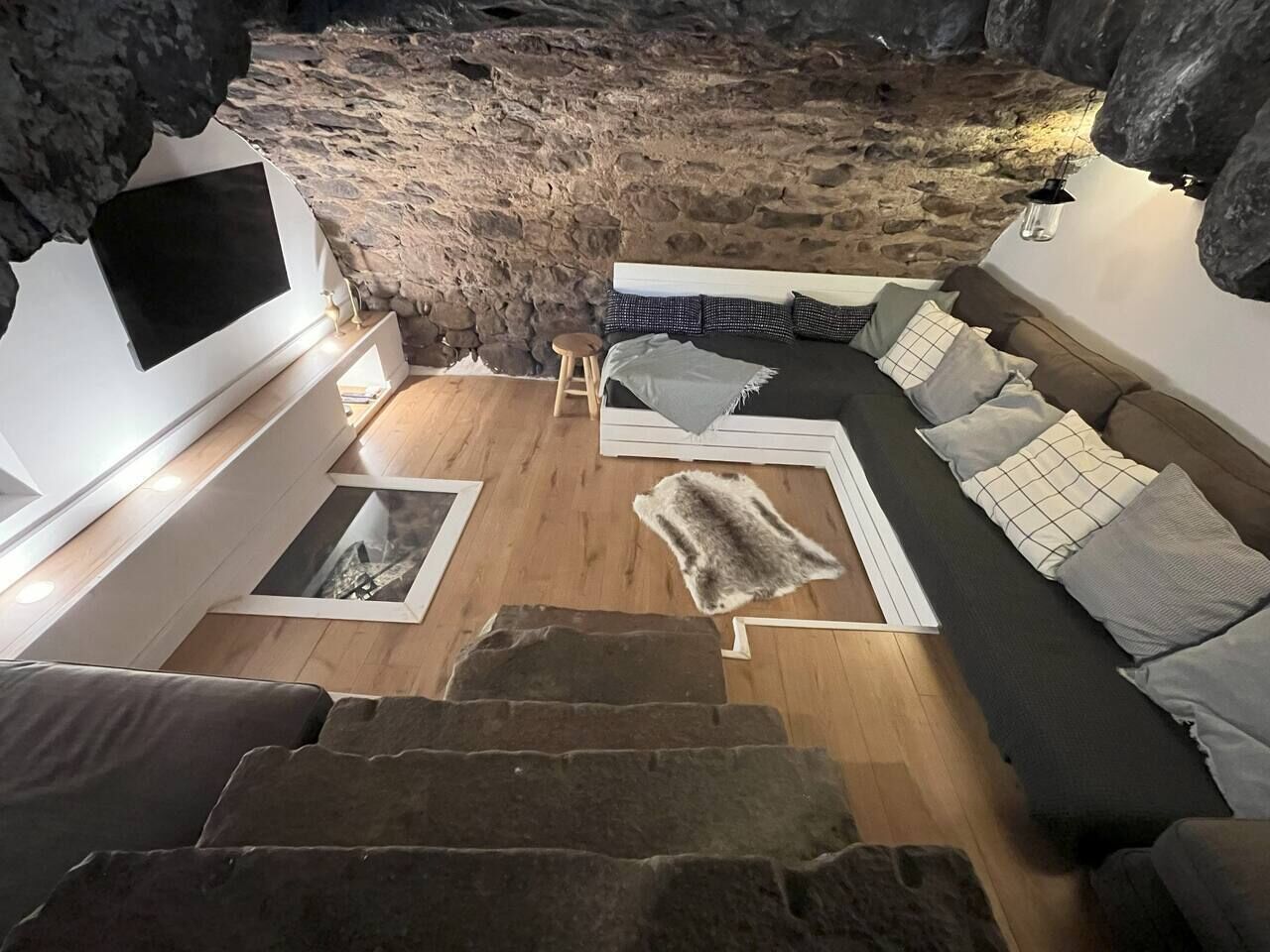 Un salon moderne avec un mur en pierre, un canapé, une table basse et une cheminée.
