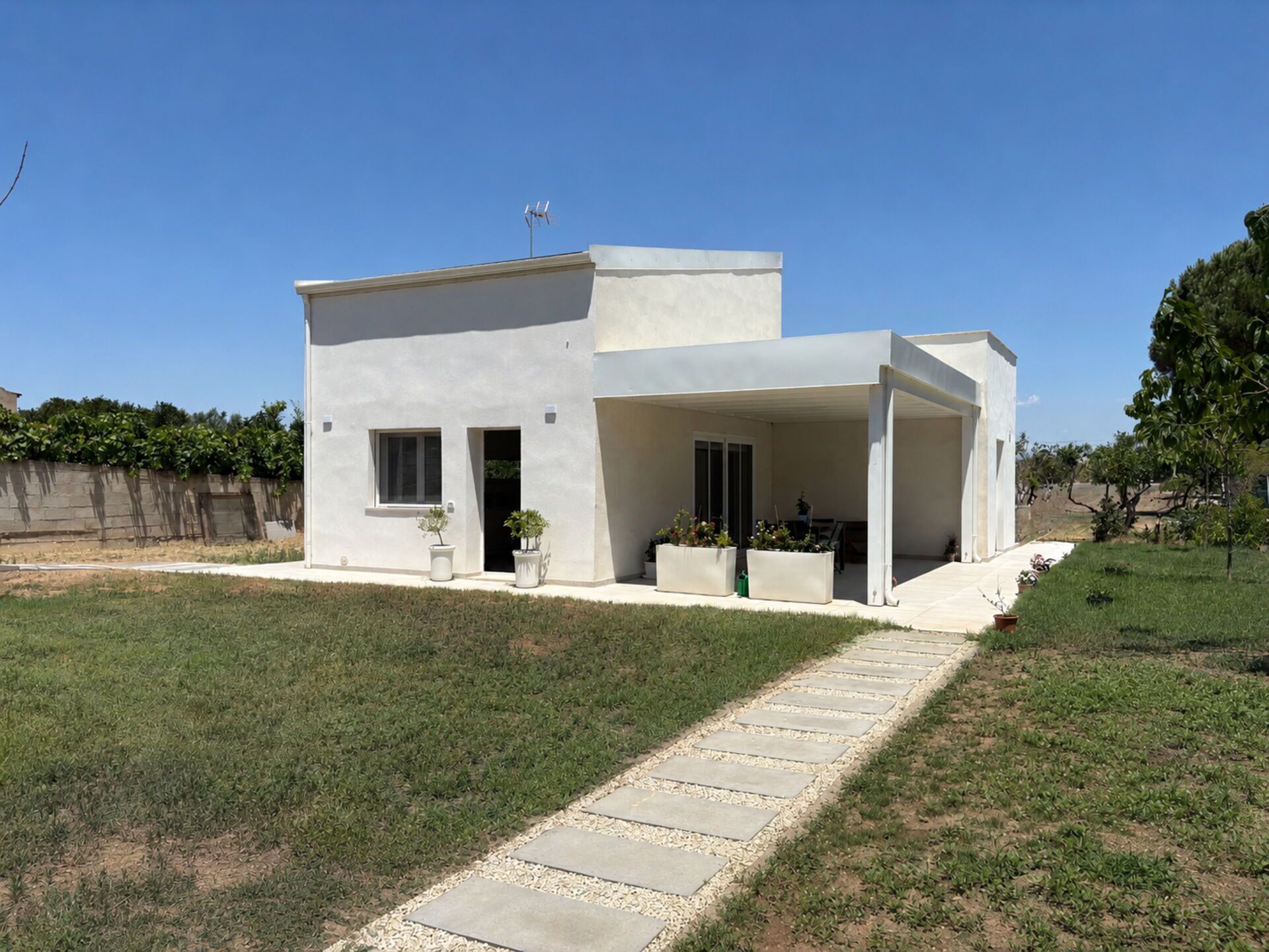 A modern two-story house with a covered patio, a paved driveway, and a well-maintained lawn.