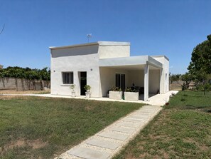 Ein modernes, zweistöckiges Haus mit überdachter Terrasse, befestigter Auffahrt und gepflegtem Rasen.