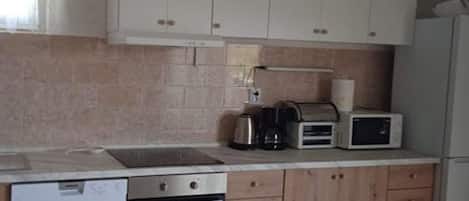 A kitchen with white cabinets, a microwave, a coffee maker, and a dishwasher.