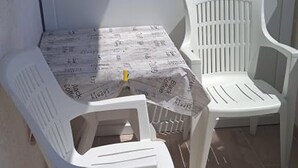 En liten sittplats utomhus med ett bord och två vita plaststolar.