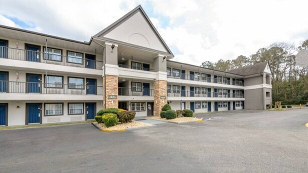 A multi-story hotel with a central lobby, multiple balconies, and a parking lot.