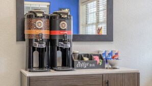 A coffee bar with two coffee dispensers, a coffee mug, and a box of coffee creamer.