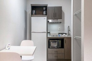 A compact kitchenette with a refrigerator, microwave, and oven, a small countertop, and a chair. - 1 Queen Bed|Non-Smoking,Kitchen (Columbus GA)