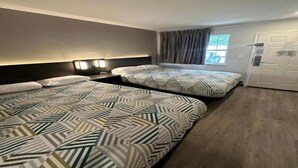Een hotelkamer met twee bedden, een raam met gordijnen, een deur en een plafondlamp.