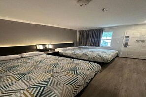 Ein Hotelzimmer mit zwei Betten, einem Vorhangfenster, einer Tür und einer Deckenleuchte.
